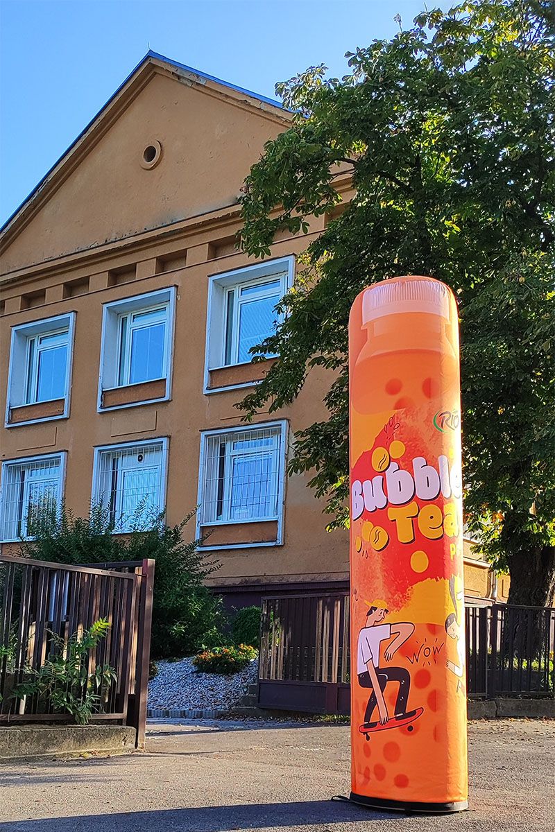 Reklamní sloup v oranžové barvě u školy na Einsteinově ulici