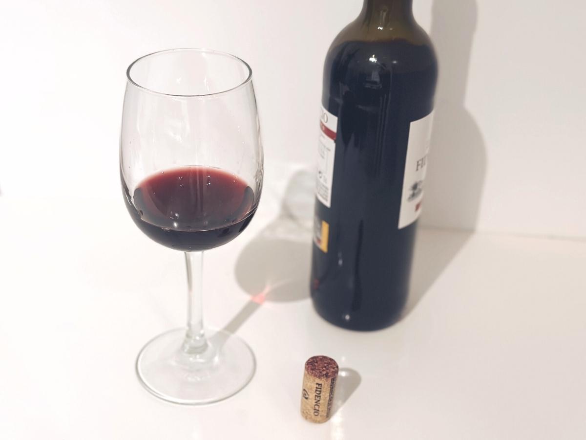 Pohár červeného vína při otevřené láhvi vína.