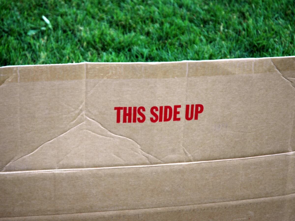 Kartonový balík označený etiketou „this side up“ (touto stranou nahoru).