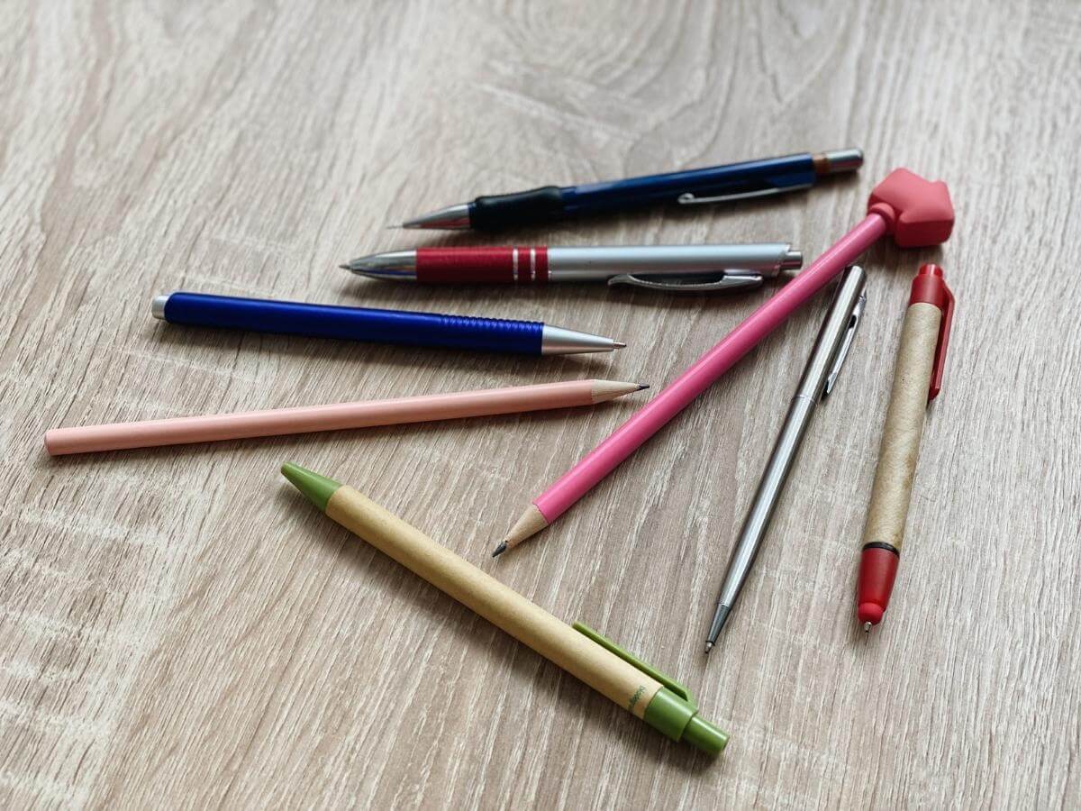 Různá pera a tužky položené na zemi.