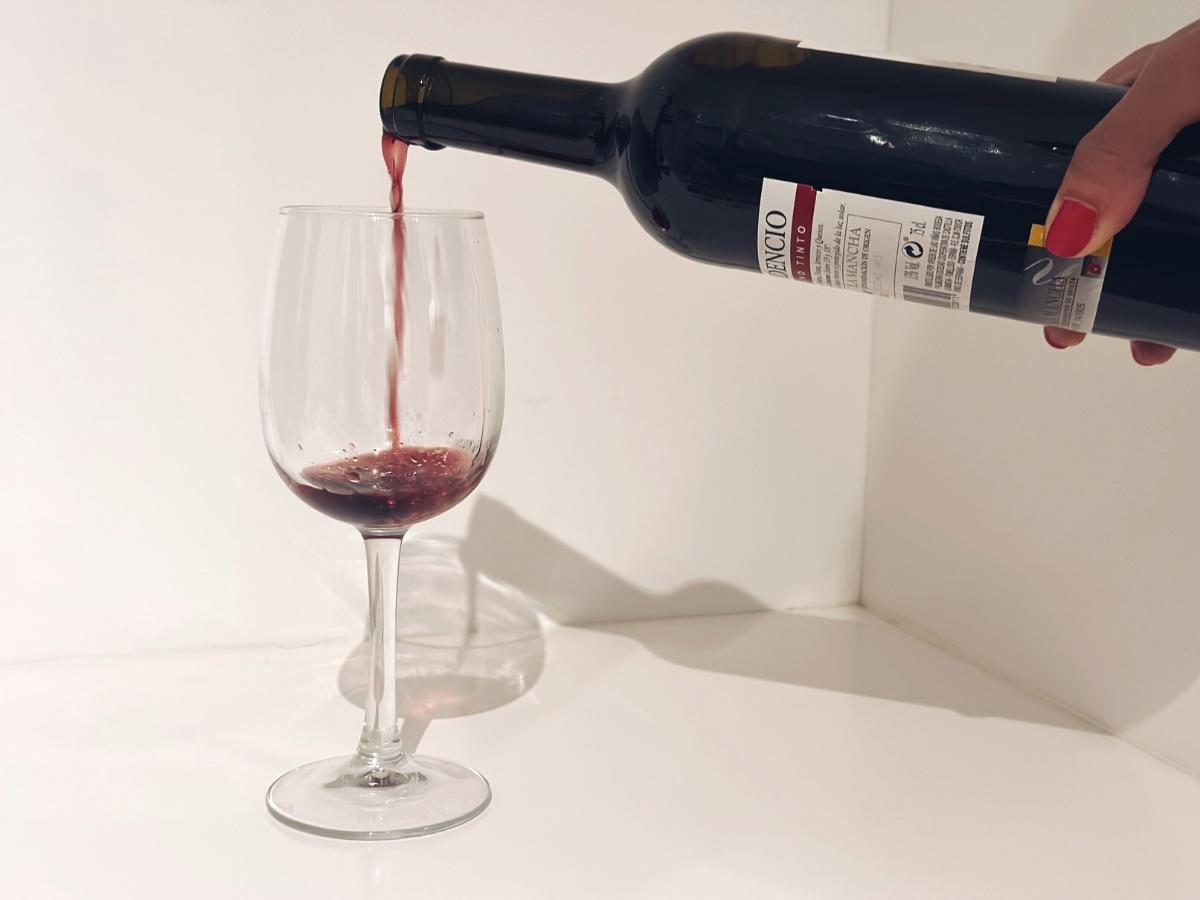 Nalévání červeného vína do sklenice.