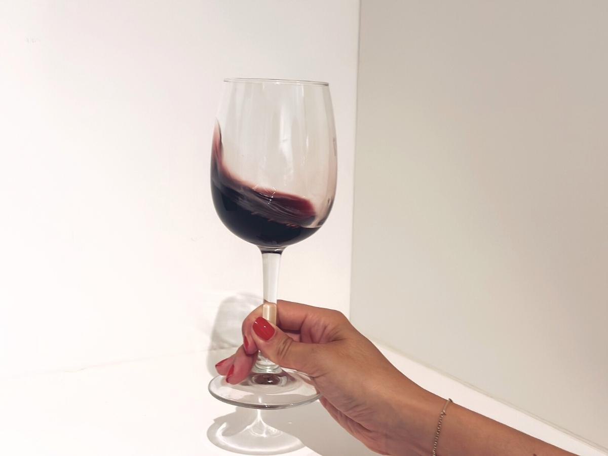 Víření červeného vína ve sklenici.