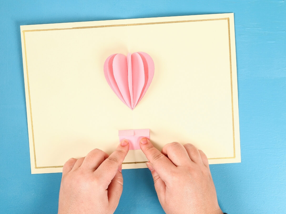 Výroba balónu z růžového papíru na svatební pohlednici.